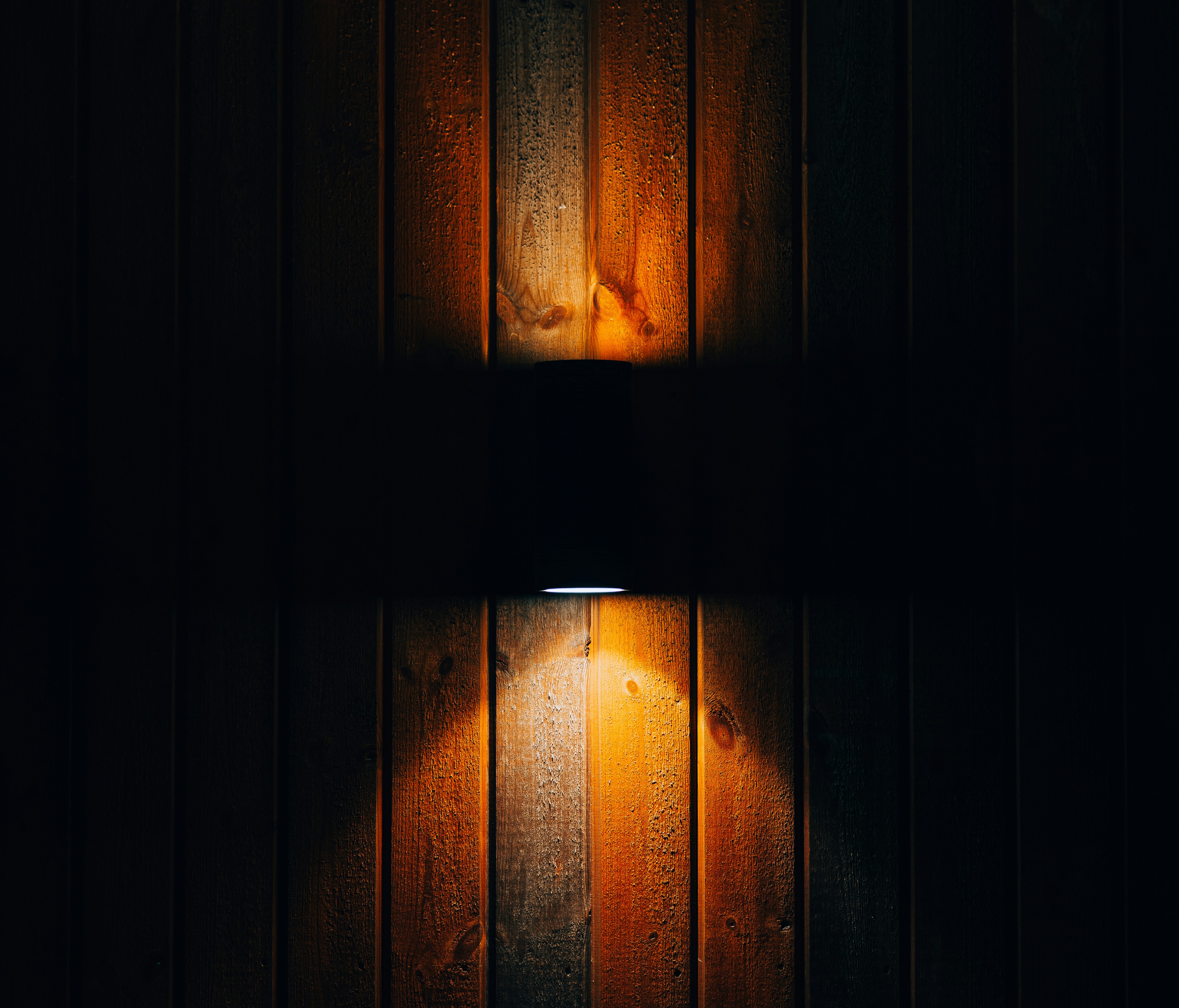 a lamp shines brightly on a wooden wall