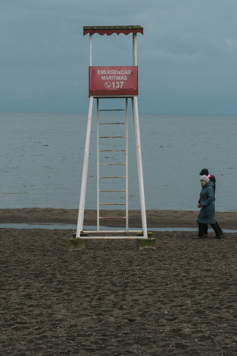 a person walking on a beach next to a lifeguard tower