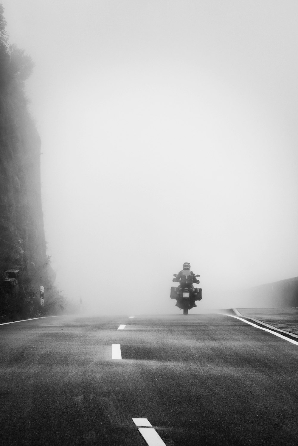 a person riding a motorcycle on a foggy road
