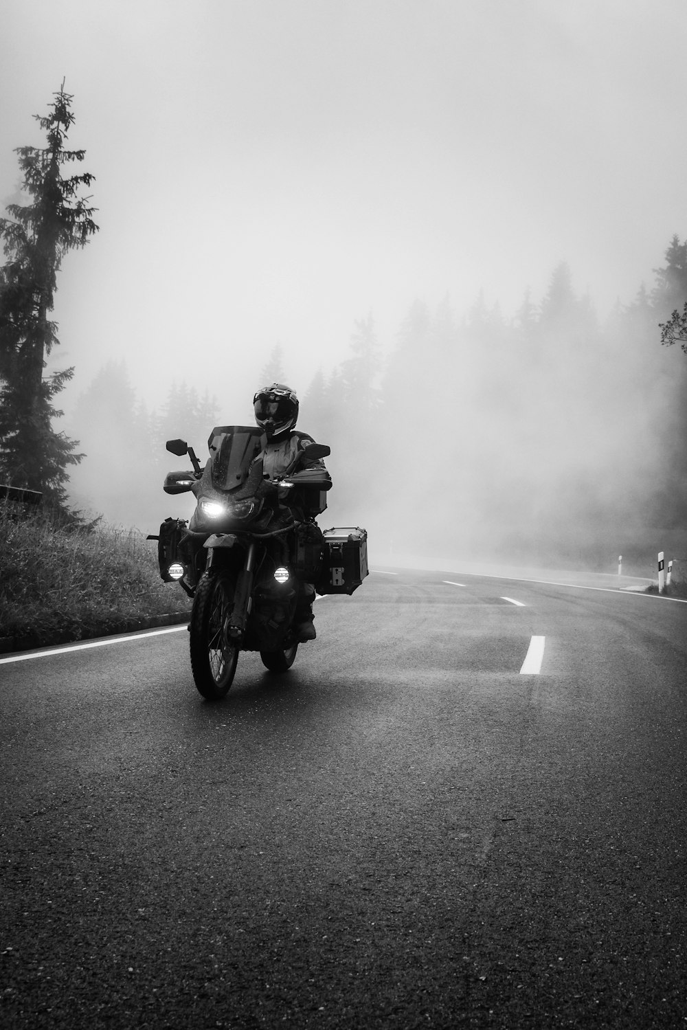 a man riding a motorcycle down a foggy road
