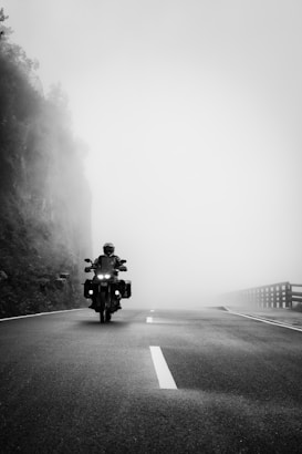 a person riding a motorcycle on a foggy road