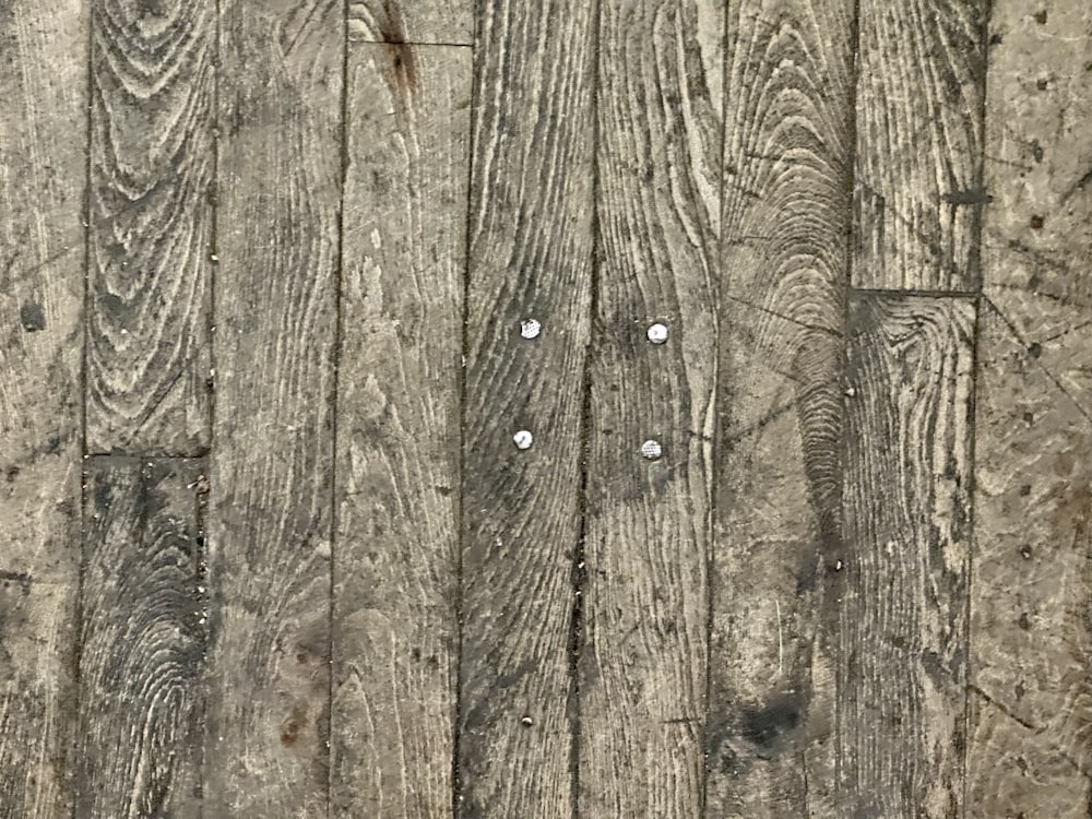 a close up of a wooden floor with nails on it