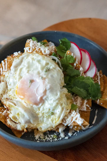 A vibrant plate of traditional chilaquiles topped with fresh cilantro and crumbled cheese.