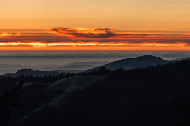 Landscape shot of rolling hills under a vibrant sunset sky