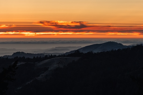 A breathtaking landscape featuring a vibrant sunset over rolling hills.