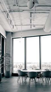 A modern glass-top table surrounded by minimalist chairs in a bright, airy space.