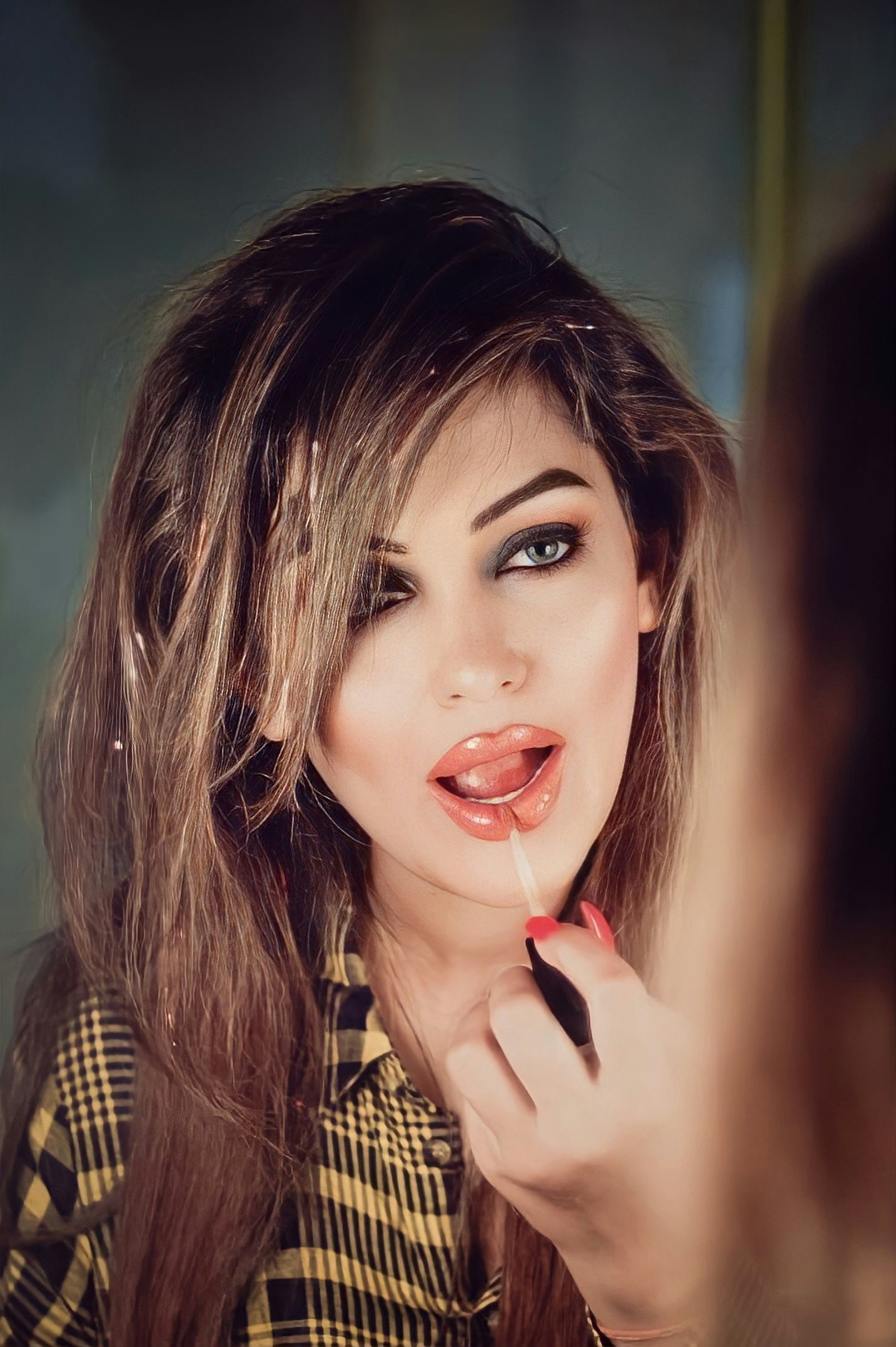 Girl applying lip gloss facing mirror