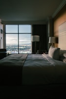 A cozy hotel room with warm lighting and a view of a historic city skyline.