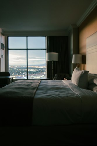A cozy hotel room with a made bed and a window, booked at the last minute