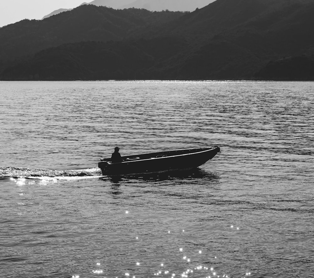 eine Person in einem kleinen Boot auf einem großen Gewässer