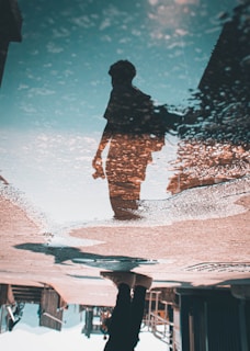 a reflection of a person in a puddle of water