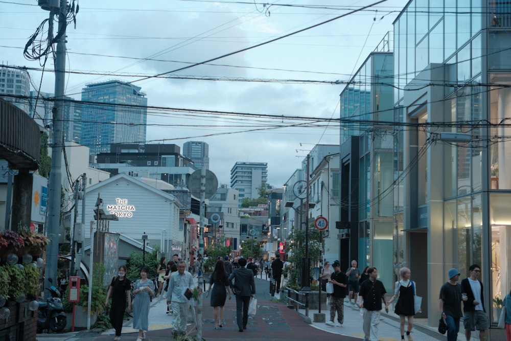 a group of people walking down a street next to tall buildings