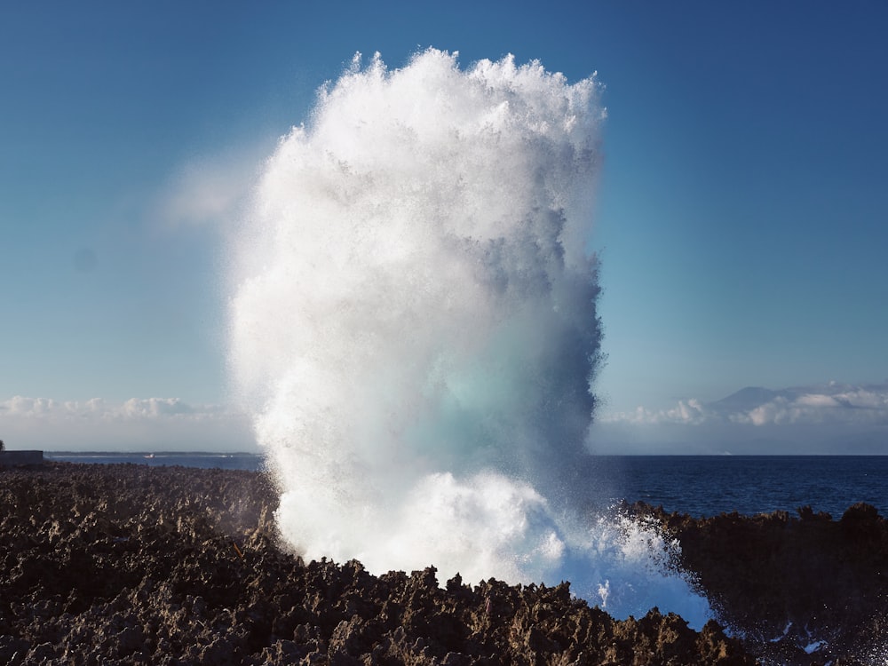 a large wave crashing into the ocean on a sunny day