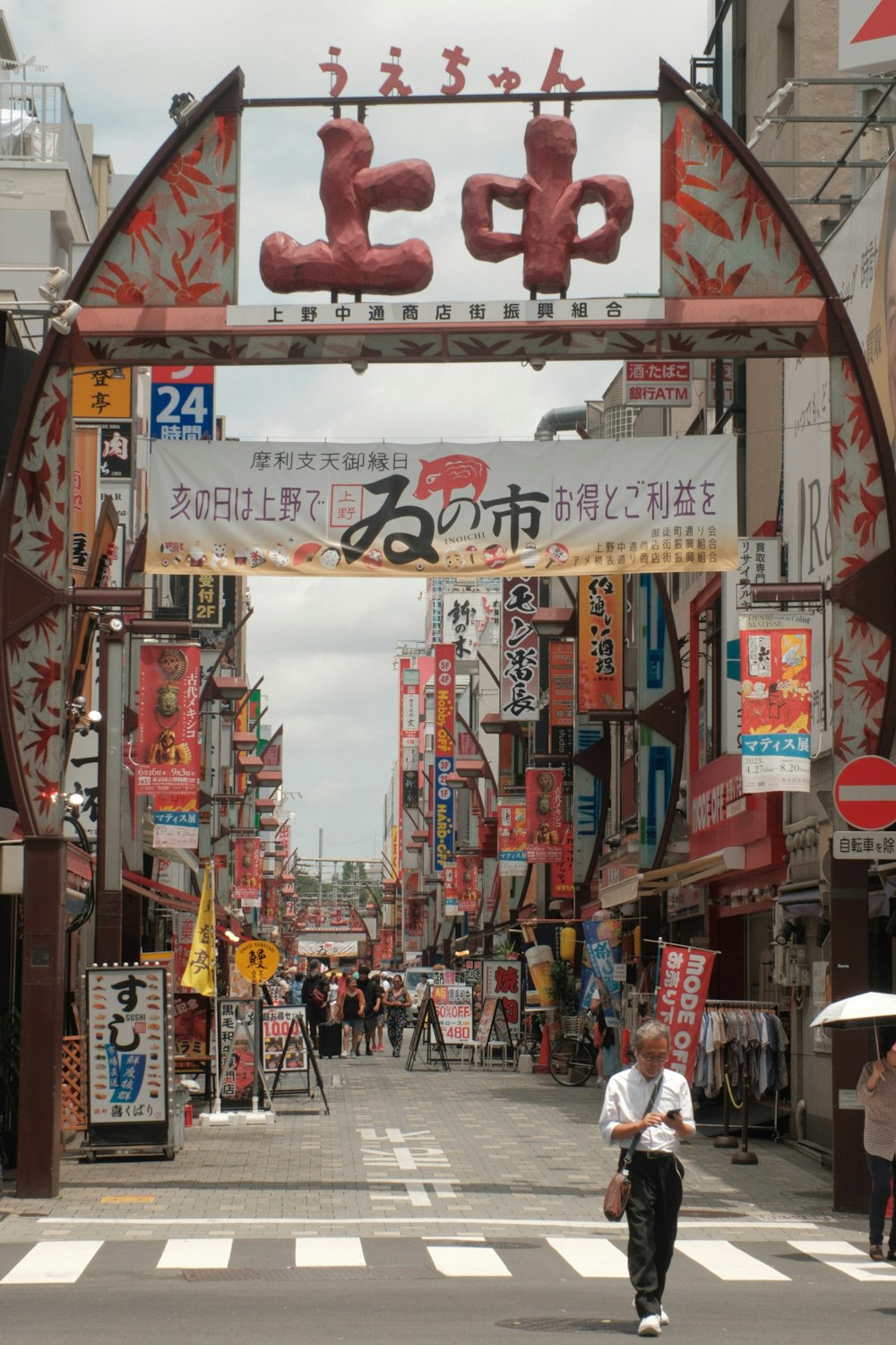 a man walking down a street under a sign