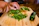 Close-up of a sleek MARU JIN knife slicing through fresh vegetables on a wooden board.