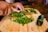 Hands preparing organic vegetables on a rustic wooden cutting board.