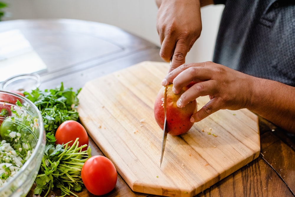 a person cutting up an apple on a cutting board