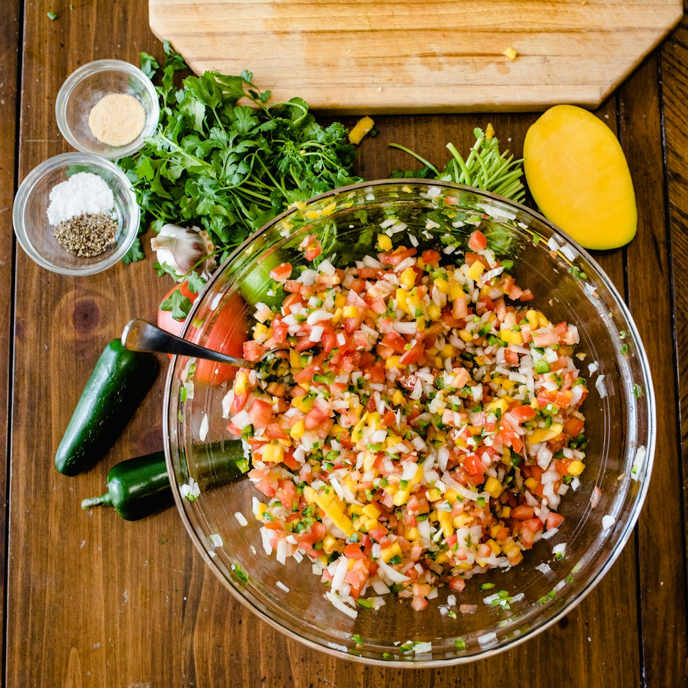 a bowl filled with chopped vegetables next to a cutting board