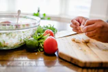 Silhouetted hands preparing fresh ingredients on a clean countertop.
