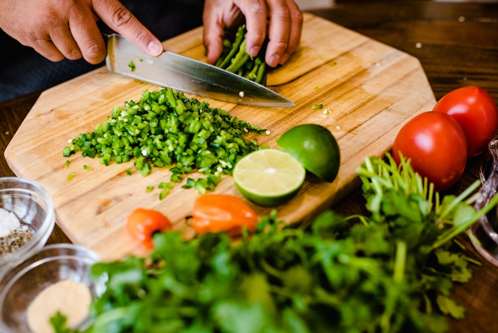 a person cutting up vegetables on a cutting board