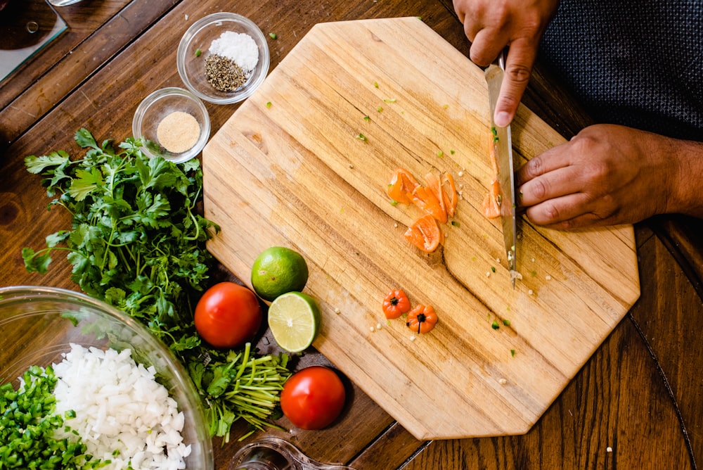 a person cutting up food on a cutting board