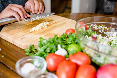 A compact electric food chopper mid-action with fresh vegetables around it.