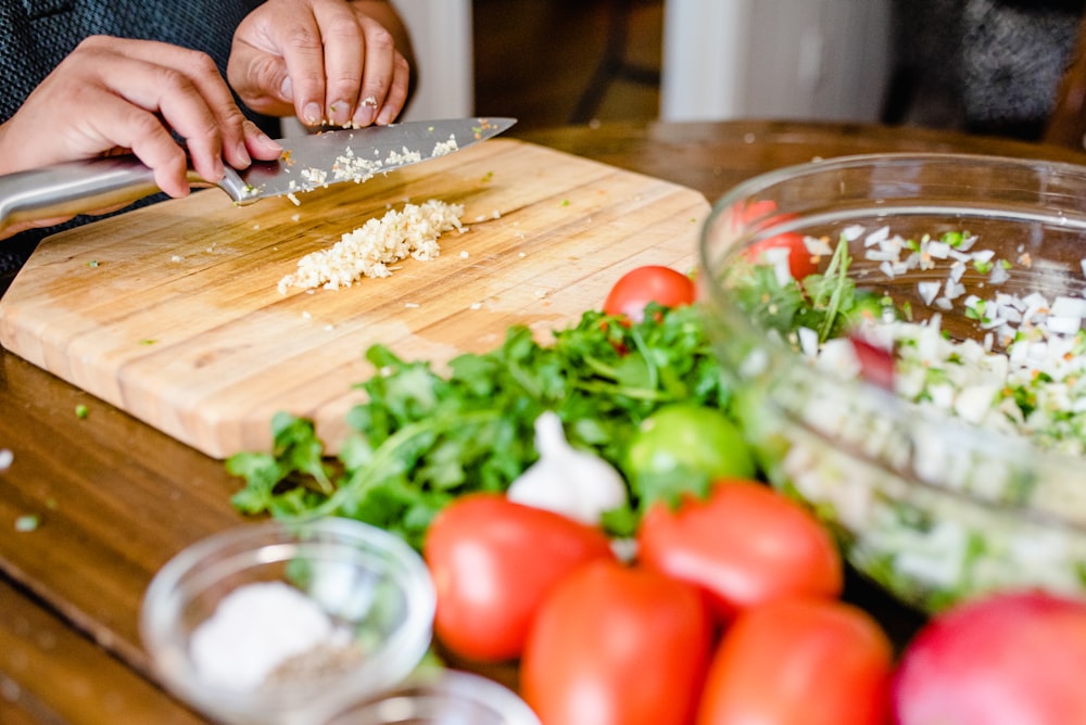 a person cutting up some food on a cutting board