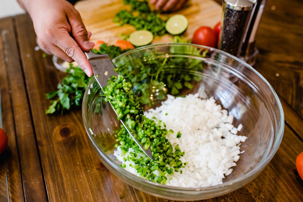 a person cutting up vegetables in a bowl