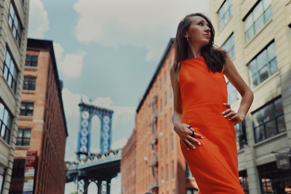 a woman in an orange dress standing in the middle of a street