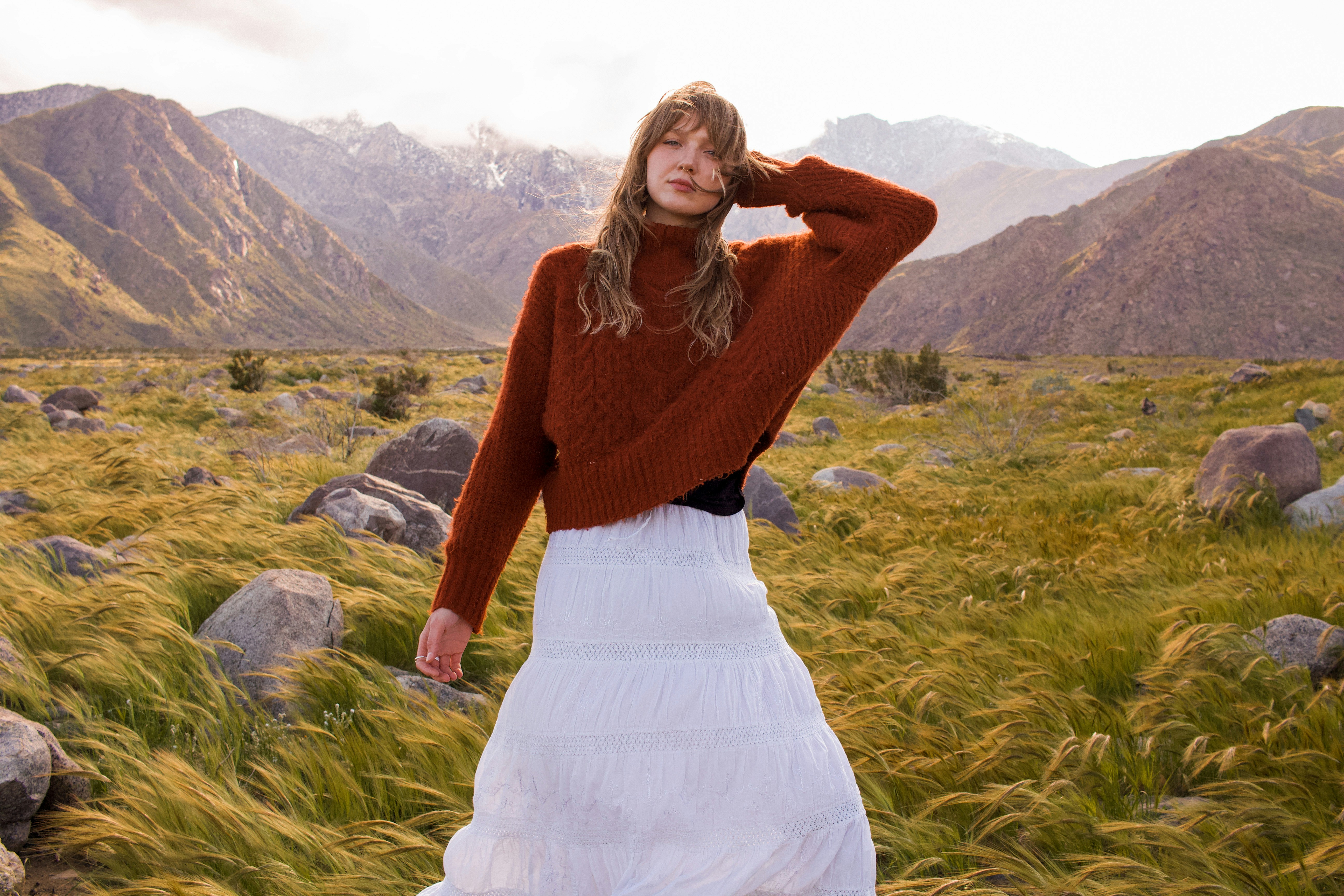 eine frau, die auf einem feld mit bergen im hintergrund steht