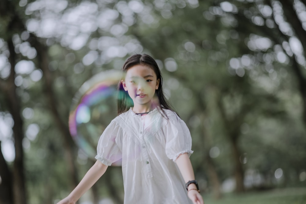 a young girl in a white dress playing with a frisbee