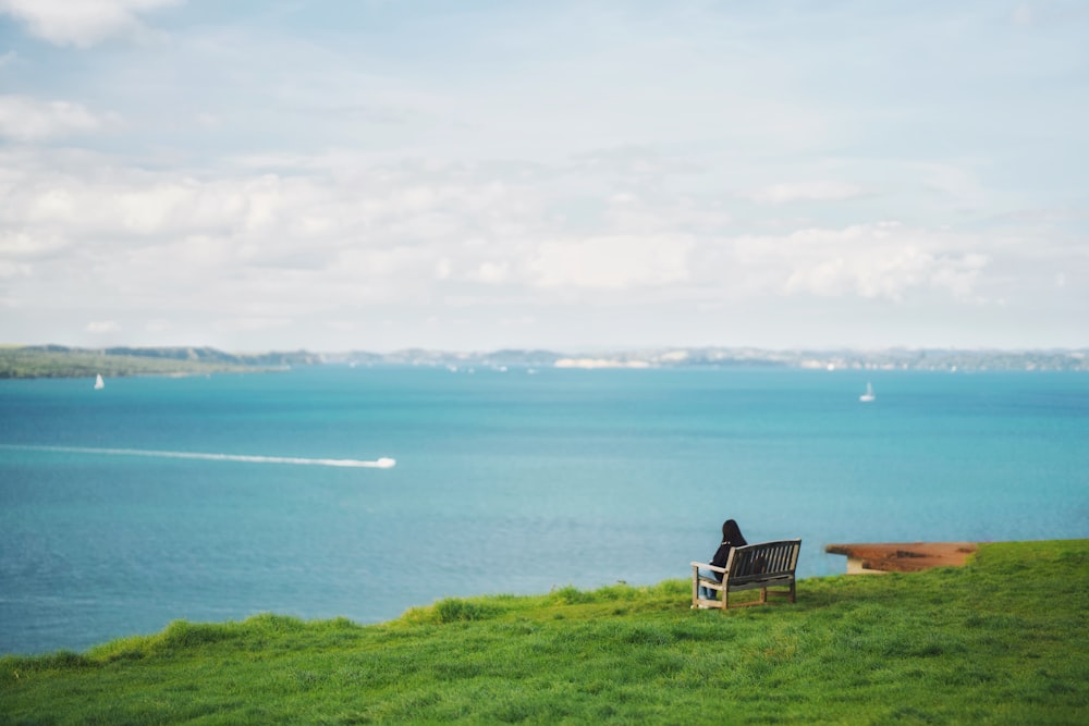 uma pessoa sentada em um banco com vista para o oceano