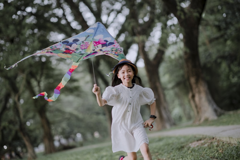 a little girl running with a kite in a park