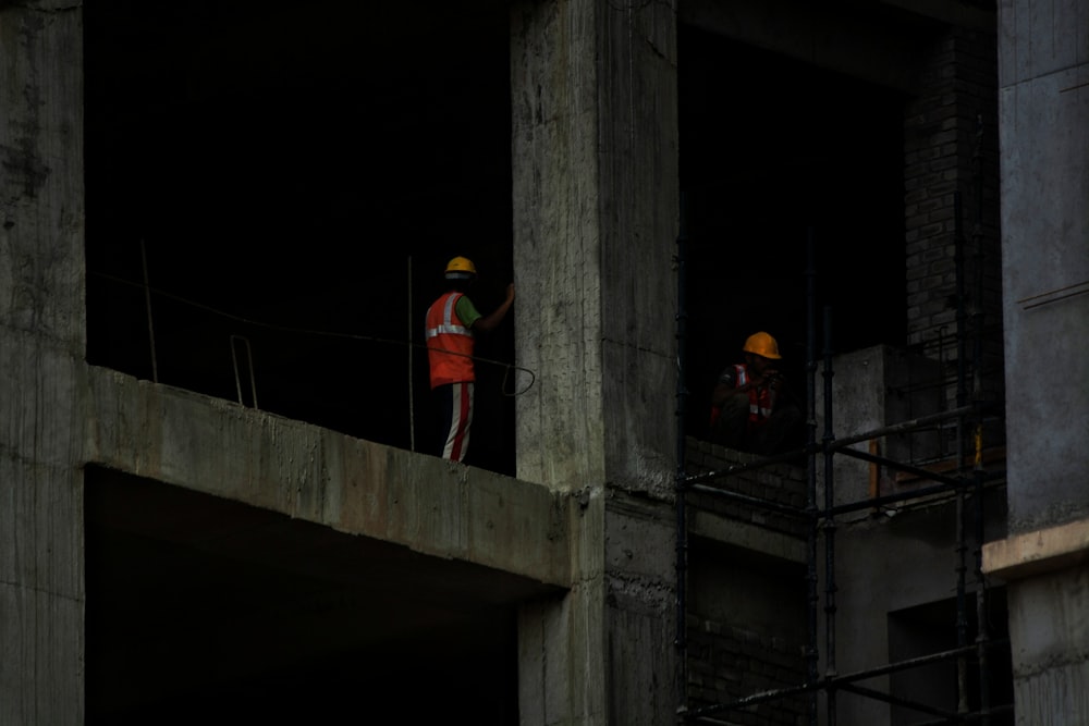 two construction workers standing on a building under construction