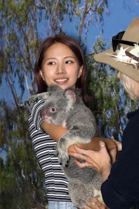 a woman holding a koala in her arms
