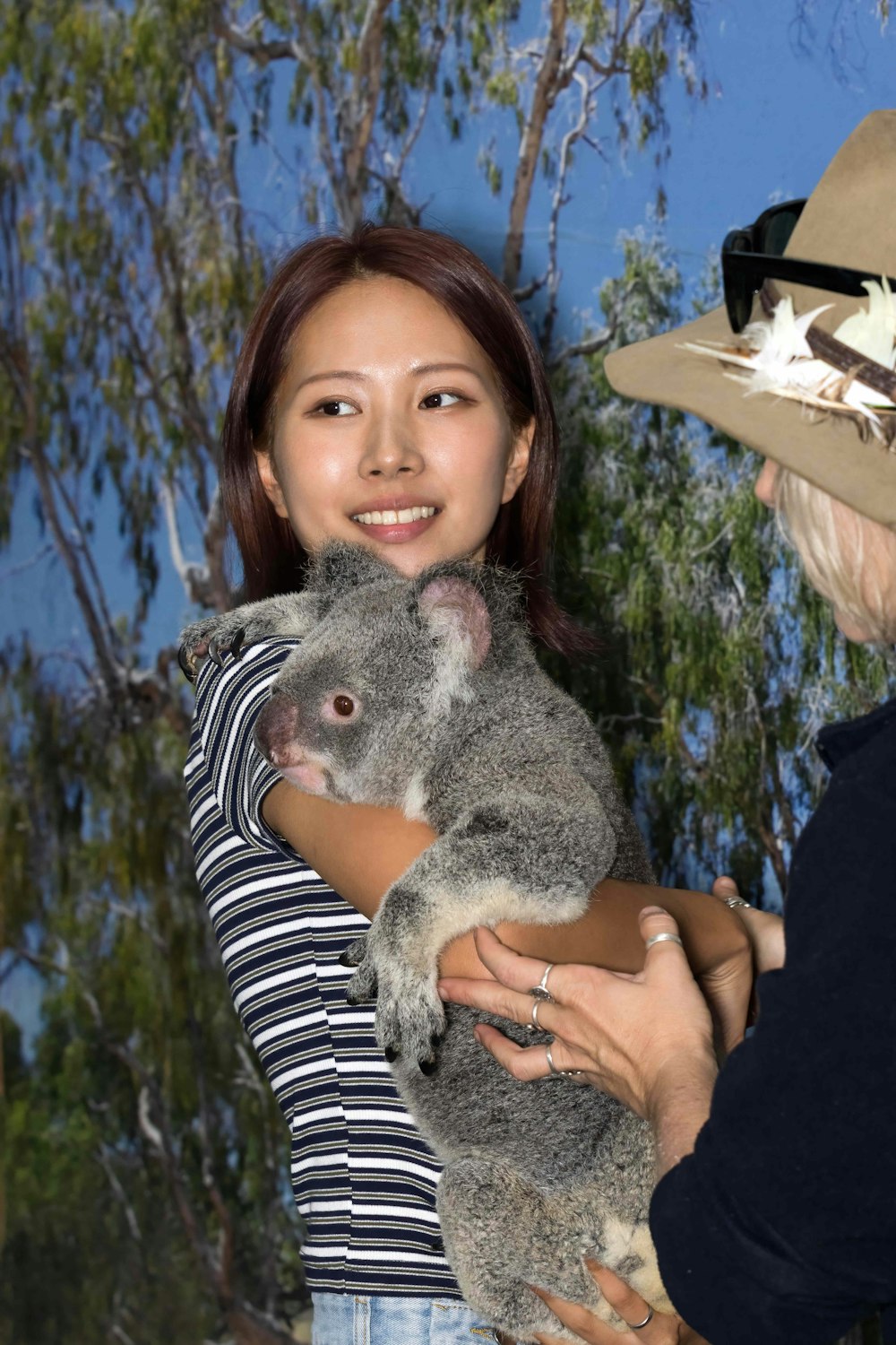 Una mujer sosteniendo un koala en sus brazos