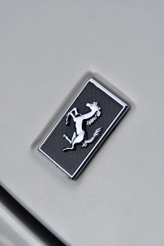 Close-up of a sleek, geometric horse head logo in champagne gold on a slate grey background.