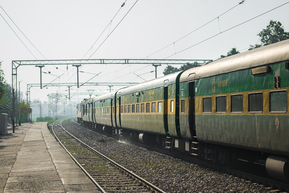 a green and yellow train traveling down train tracks