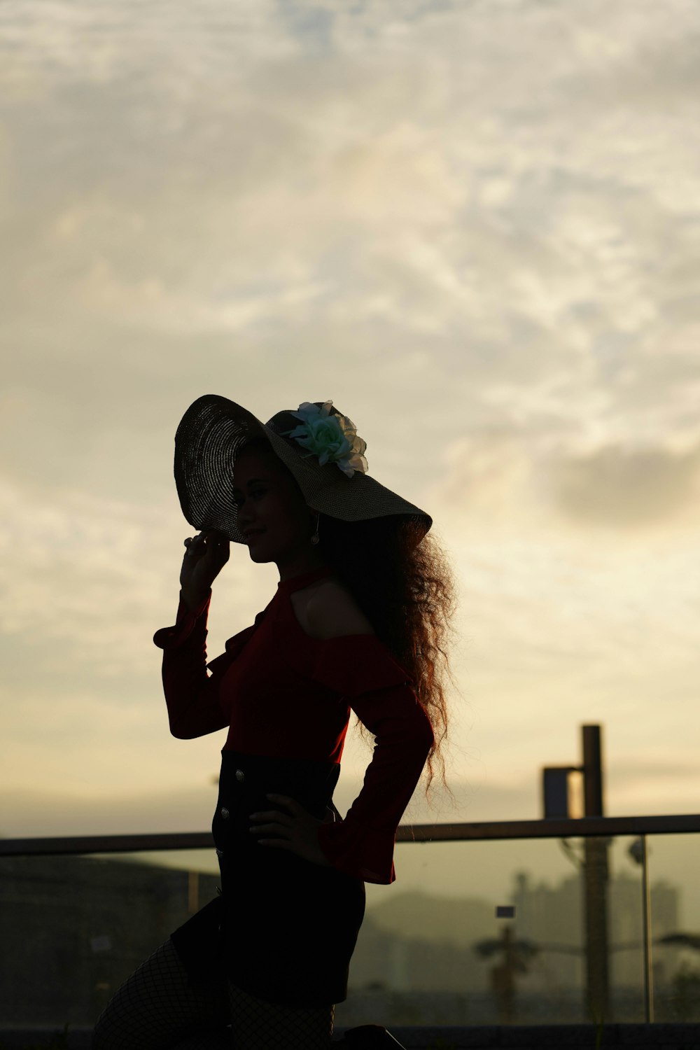 a woman in a hat is standing on a balcony