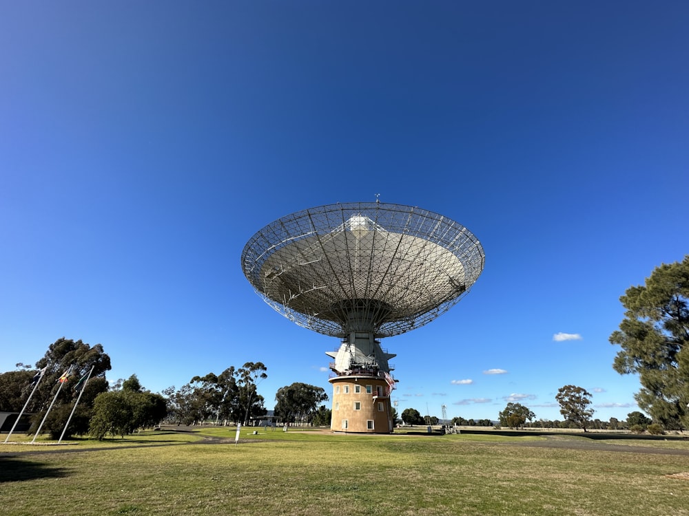 Una gran antena parabólica sentada en la cima de un exuberante campo verde