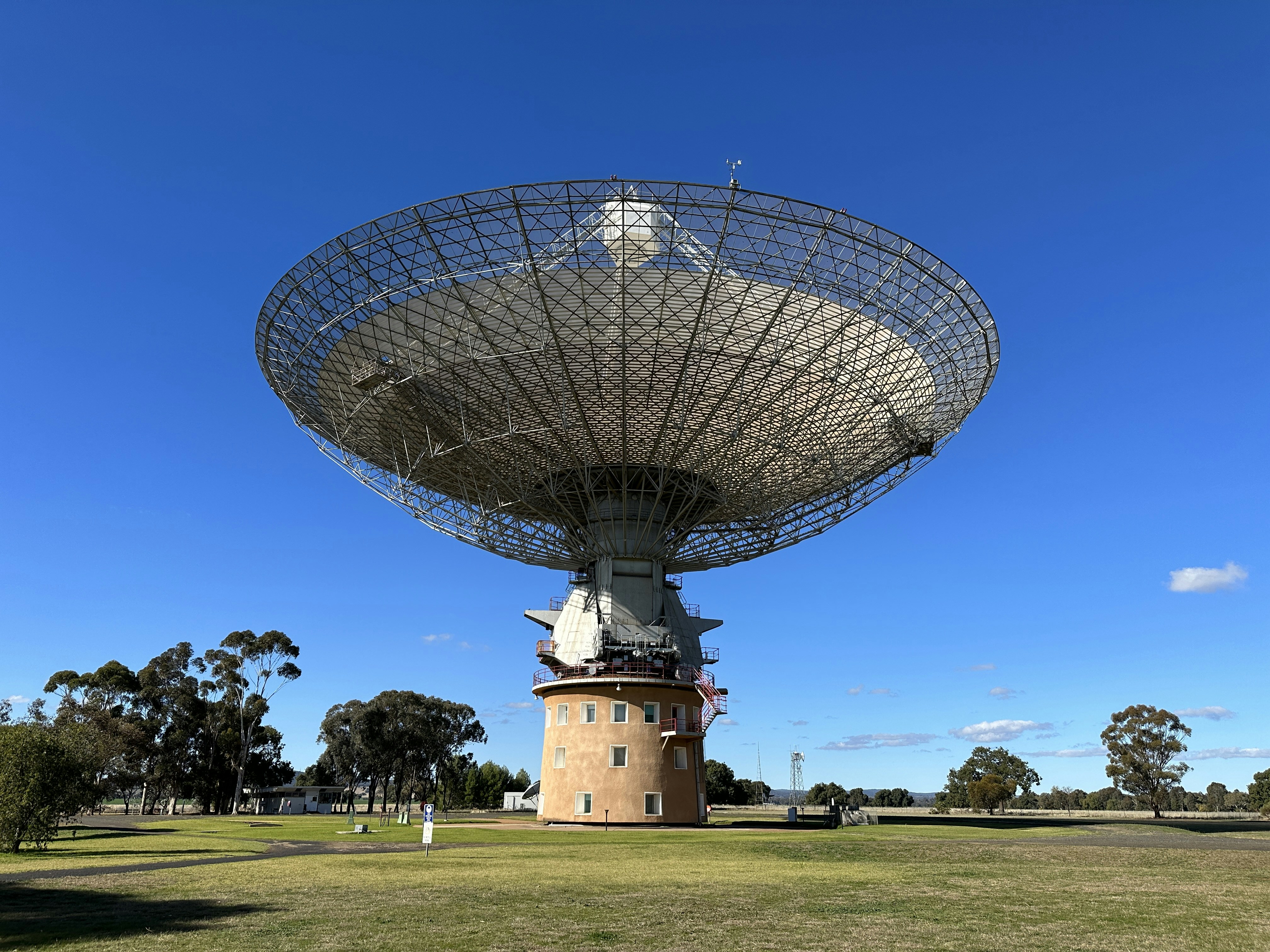 a large satellite dish sitting on top of a lush green field
