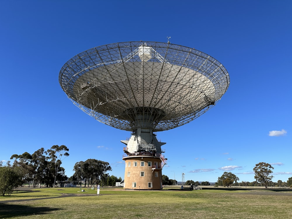 a large satellite dish sitting on top of a lush green field