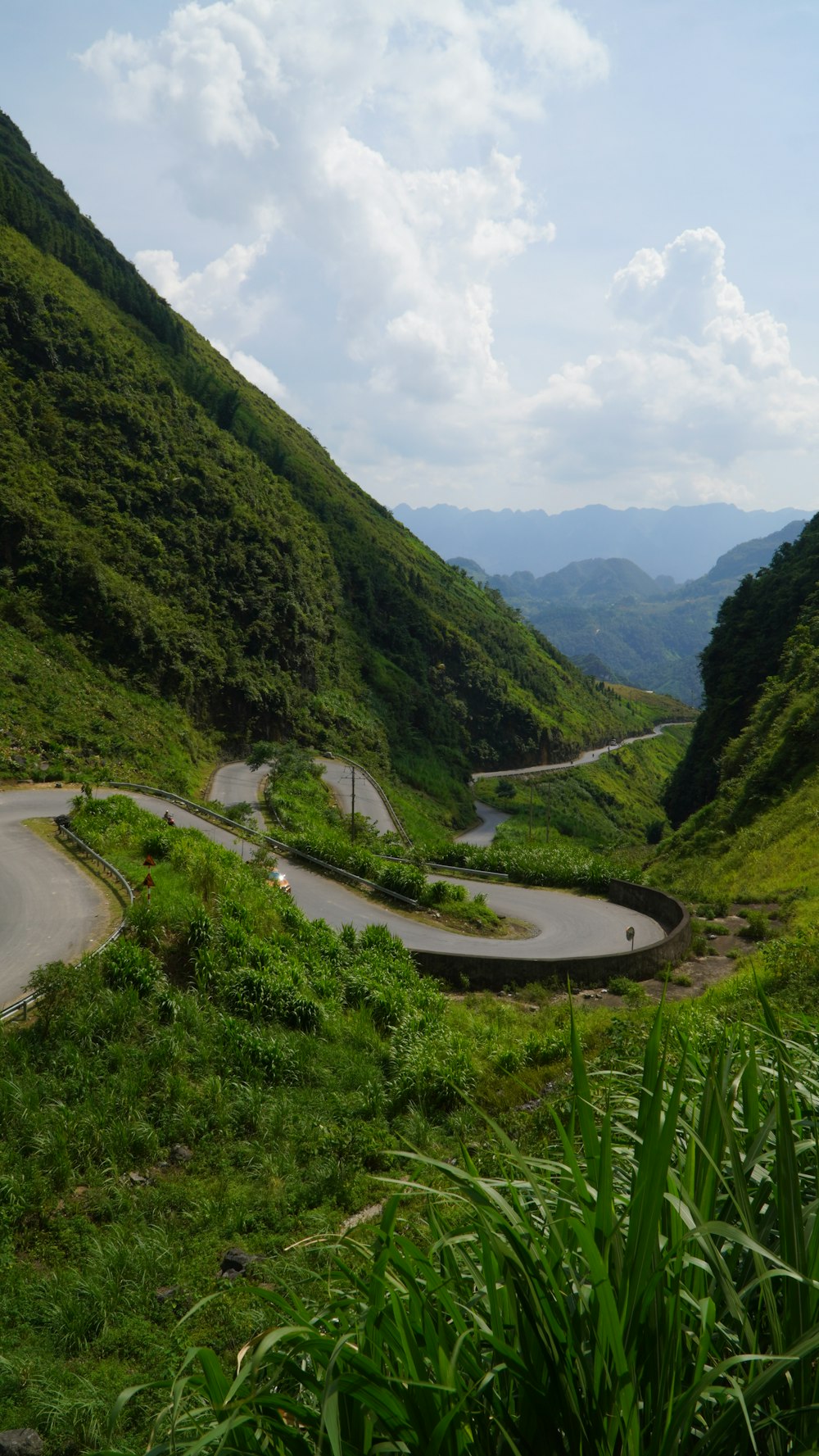 a winding road in the middle of a lush green valley