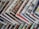 An array of colorful magazines or newspapers is spread out. Each publication features vibrant and varied cover designs, with a mix of illustrations, text, and patterns. The arrangement creates a visually dynamic and layered appearance.