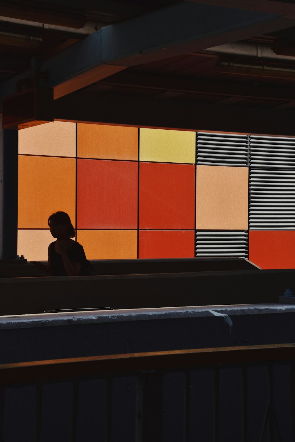 a woman sitting in front of a colorful wall