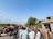 A community meeting in a rural village setting with people engaged in discussion.