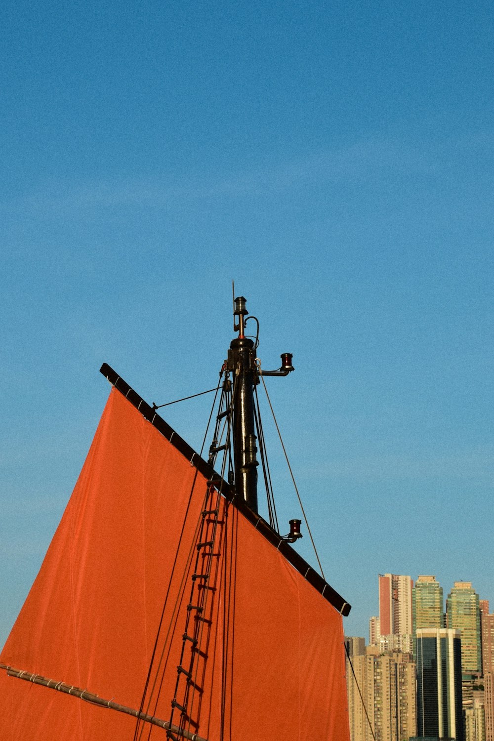 a large red sail boat in front of a city skyline