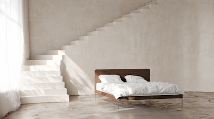 a bed sitting under a stair case next to a window