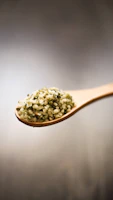A handful of flax seeds resting on a wooden spoon with a soft-focus background.