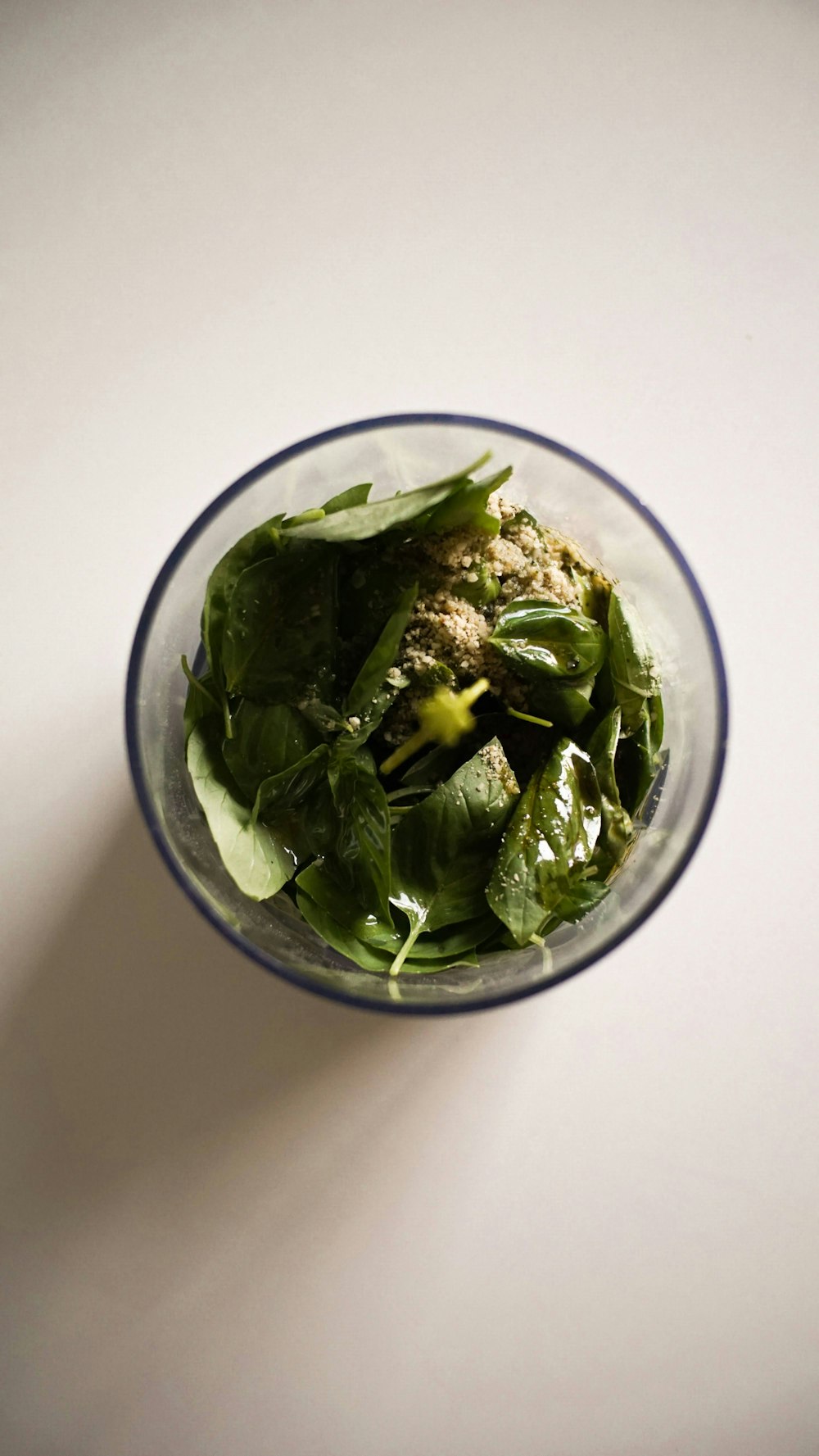 a glass bowl filled with spinach and meat